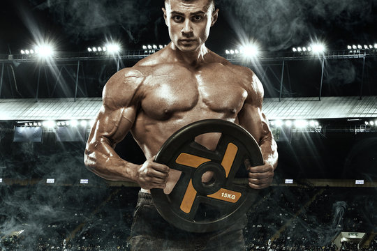 Brutal strong muscular bodybuilder athletic man pumping up muscles workout bodybuilding concept background - handsome men doing exercises in gym naked torso. Copy space for sport nutrition ads.