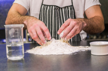 Man preparing pizza dough on black granite table