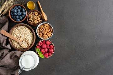 Fototapeta na wymiar Nutrition Healthy Eating Ingredients on Black Concrete Background. Oats, Berries, Nuts, Almon Milk and Raw Honey. Healthy eating, Healthy lifestyle, Dieting
