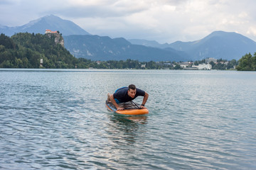 young man exercising on paddle board at the lake