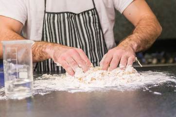 Obraz na płótnie Canvas Man preparing pizza dough on black granite table