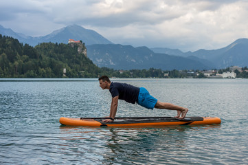 young man exercising on paddle board at the lake