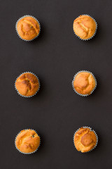 Closeup of homemade vanilla muffins places in rows on black background. Healthy snack.