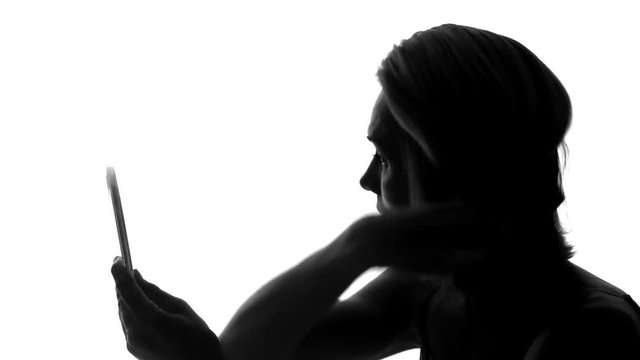 Unattractive woman sitting, looking at mirror, brushing gray, problematic hair