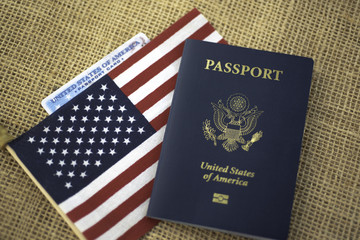 Passport card of USA covered by American Flag next to US international passport on burlap  surface.