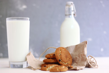 cookies with milk breakfast concept with glass and bottle of milk on light background and wooden table