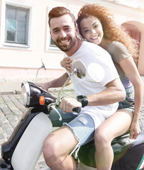Obraz premium Cheerful young couple riding a scooter and having fun