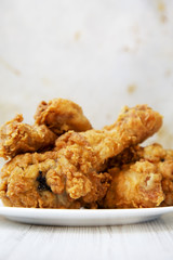 Fried chicken legs on a white round plate, closeup. Side view.