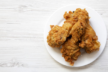 Fried chicken legs on a white round plate with copy space, top view. From above, overhead, flat lay.