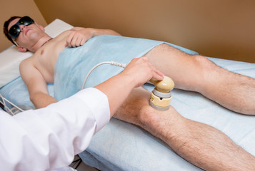 Ultrasound treatment in physical therapy. Physiotherapist doctor using laser to treat the joints and muscles of a patient.