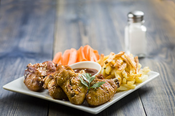 chicken wings with sesame surrounded by fries and carrots