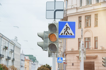 Road sign of a pedestrian crossing and traffic light with yellow light