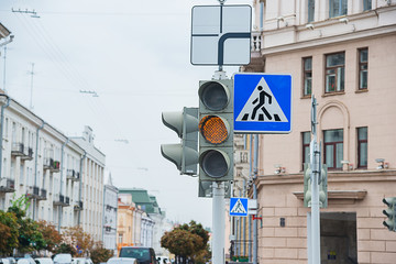 Road sign of a pedestrian crossing and traffic light with yellow light