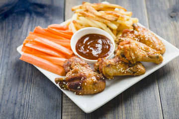 chicken wings with sesame surrounded by fries and carrots