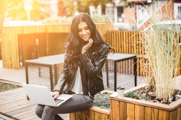 Happy latin woman with smartphone or laptop in city centre