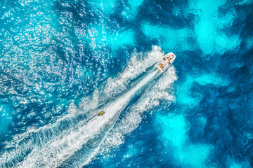 Motorboat at the sea in balearic islands. Aerial view of floating boat with people in transparent...