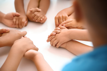 Fototapeta na wymiar Little children holding hands at table, closeup. Unity concept