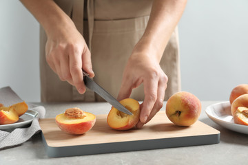 Woman cutting fresh sweet peaches on table