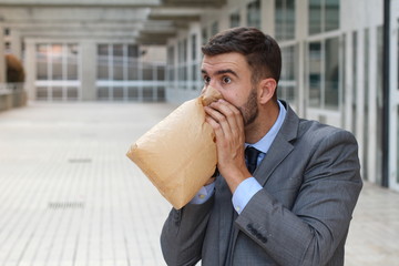 Stressed out man breathing through paper bag 