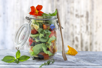 Vegan salad in a jar: vegetables,and flowers,pasta for a healthy homemade raw food concept.