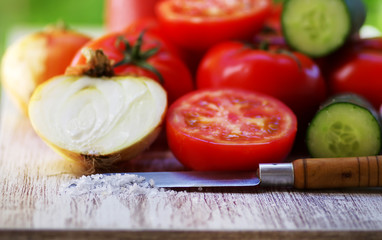 Red tomatoes , onion, salt, kitchen knife on table
