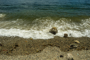 white wave washing the rock on the sandy beach
