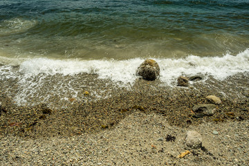 white wave washing the rock on the sandy beach