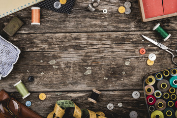 Set of scattered sewing accessories on rustic wooden table