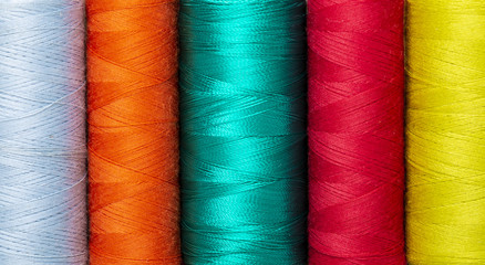 Close-up background of colorful vibrant silk threads on sewing spools