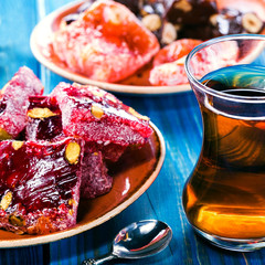 Traditional oriental sweets and traditional Turkish tea on a blue wooden background. Turkish desert-Rahat locum.square image.