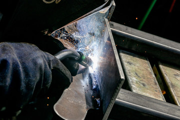 Man tig welding steel plate with brilliant bright white star burst blooms - obrazy, fototapety, plakaty