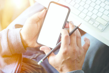 Top view shot of man holding mobile phone over workspace in office.