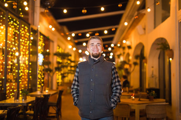 Obraz premium Young smiling guy posing at night in cafe