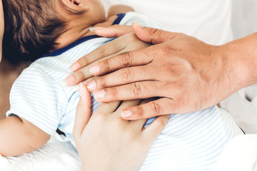 Mother and father holding baby in her arms in a white bedroom.Love of family concept