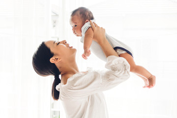 Fototapeta premium Portrait of happy smiling mother playing with baby on bedroom at home.Love of family concept