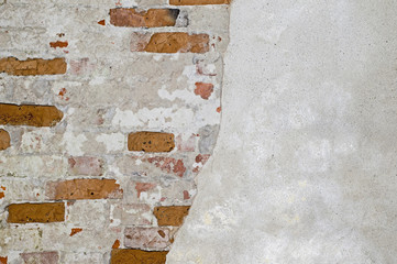 The brick wall is partially cleared from plaster to the basis of red bricks. Background, texture.