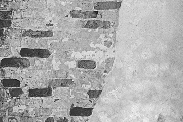 The brick wall is partially cleared from plaster to the basis of bricks. Background, texture. Black...