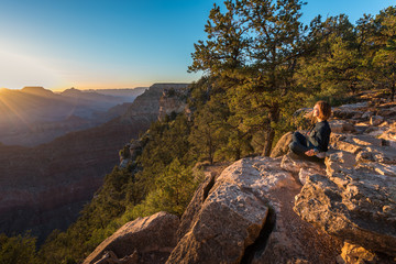 Naklejka na ściany i meble Girl is Seating and Doing Yoga on the Edge of Grand Canyon on Sunrise