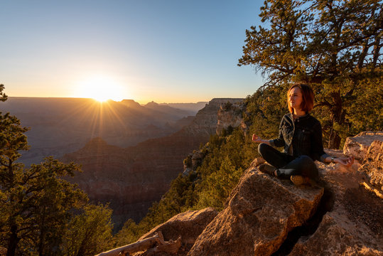 Girl is Seating and Doing Yoga on the Edge of Grand Canyon on Sunrise