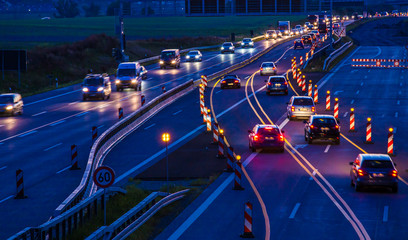 eine Autobahnbaustelle bei Nacht mit starkem Fahrzeugverkehr - obrazy, fototapety, plakaty