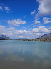 Turquoise mountain lake and blue sky with clouds