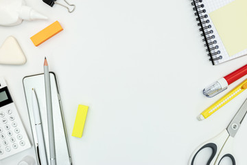 notebook, pencils, erasers, scissors and other office supplies on white desk