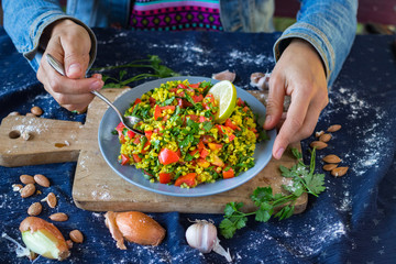 Woman hands holds Tabbouleh. Levantine vegetarian salad with parsley, tomatoes, bulgur, couscous, olive oil, lemon juice. Vegan Arabian or Israeli traditional food served as part of meze