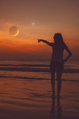 Girl looking at the star and Moon above the ocean / sea beach.