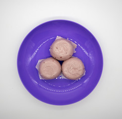 Steamed purple sweet potato Chinese buns on purple plastic plate isolated on white