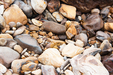 Close up of large and small sea pebble stone and colored granite at the beach. Textures, patterns, background. Close up of sea pebbles different shapes and colors.