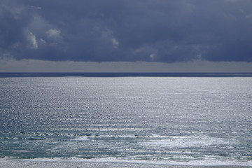 Silver light on the ocean under approaching storm clouds