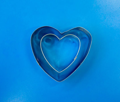 Double heart shape cookie cutter isolated on blue background.
