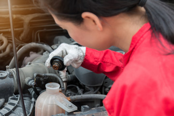 Fototapeta na wymiar Mechanic in red overalls repairing the car engine, Concept of service or repair motor car, Detail of engine, Close up of hand, Female mechanic fixing a car.
