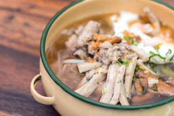 Vietnamese rice noodle soup with sliced ​​pork and chicken feet spicy soup in bowl made of coconut shell with sauce, Traditional food of Vietnamese.